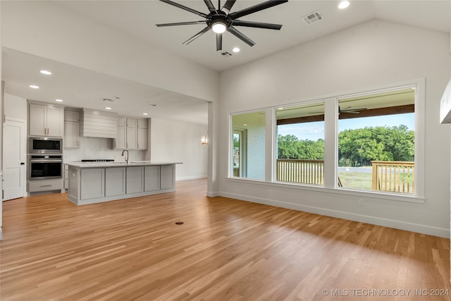 unfurnished living room with lofted ceiling, light hardwood / wood-style flooring, sink, and ceiling fan