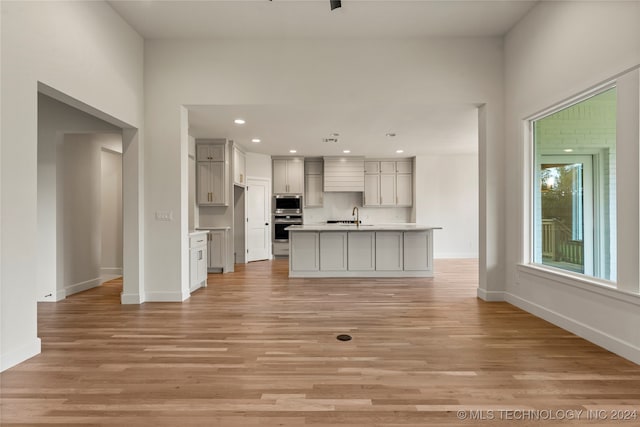 unfurnished living room with sink and light hardwood / wood-style floors