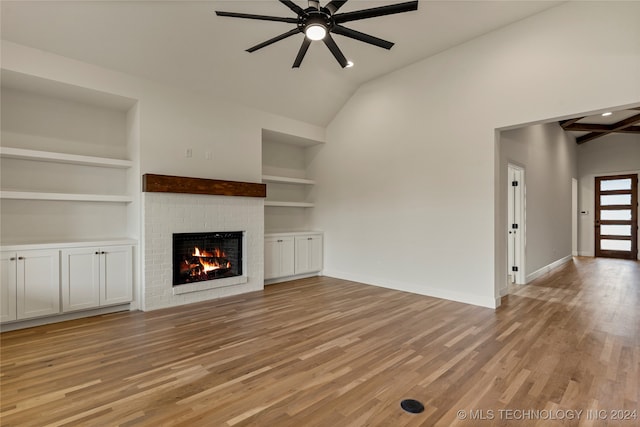 unfurnished living room featuring built in features, a brick fireplace, ceiling fan, and light hardwood / wood-style floors