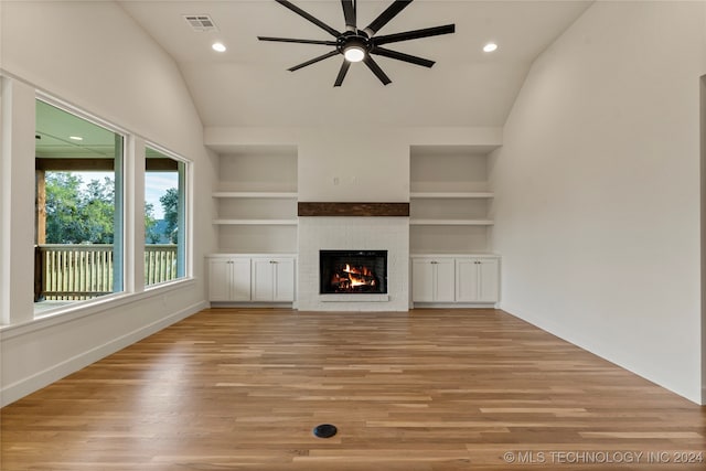 unfurnished living room featuring built in features, light hardwood / wood-style flooring, a brick fireplace, ceiling fan, and lofted ceiling