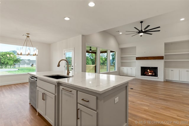 kitchen with light hardwood / wood-style flooring, ceiling fan with notable chandelier, sink, lofted ceiling, and a center island with sink