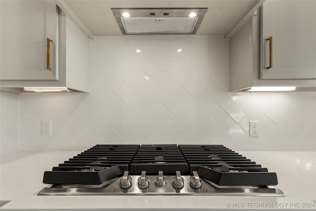 kitchen with range hood, stainless steel gas stovetop, and decorative backsplash