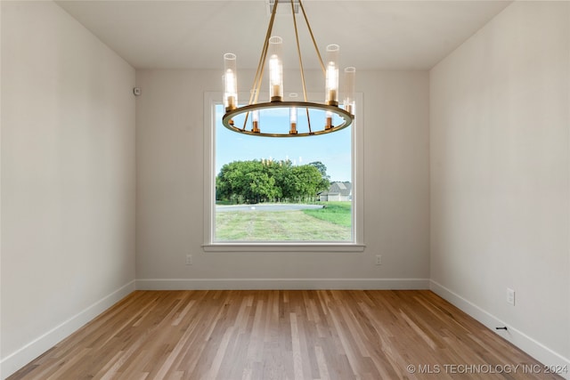 empty room featuring light hardwood / wood-style flooring and a notable chandelier