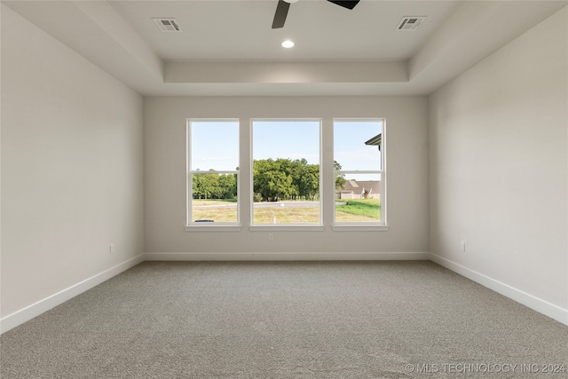 carpeted spare room featuring ceiling fan and a tray ceiling