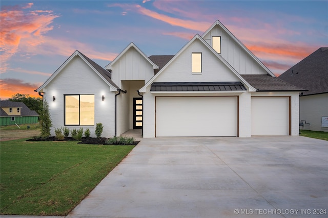 modern inspired farmhouse featuring a garage and a lawn