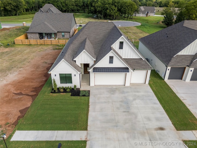 modern farmhouse featuring a front yard and a garage