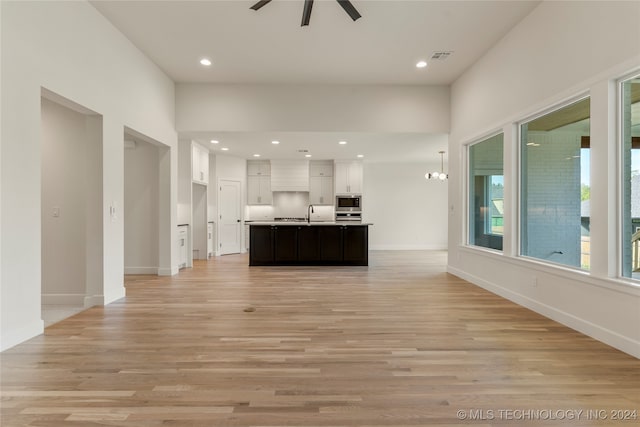 kitchen with a kitchen island with sink, white cabinetry, light hardwood / wood-style flooring, stainless steel appliances, and ceiling fan