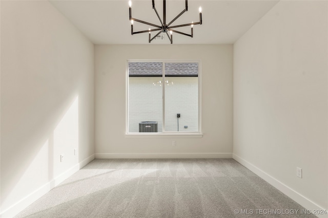 empty room with light carpet and an inviting chandelier