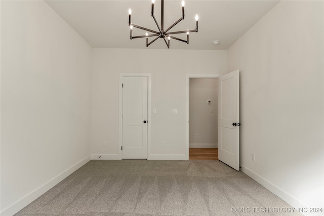 carpeted empty room featuring a chandelier