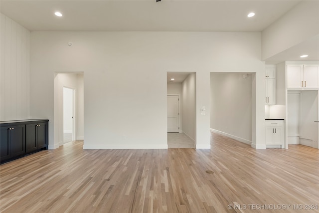 spare room with light hardwood / wood-style flooring and a towering ceiling