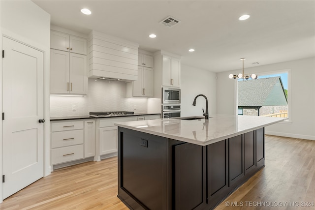 kitchen featuring pendant lighting, light hardwood / wood-style flooring, an island with sink, stainless steel appliances, and sink