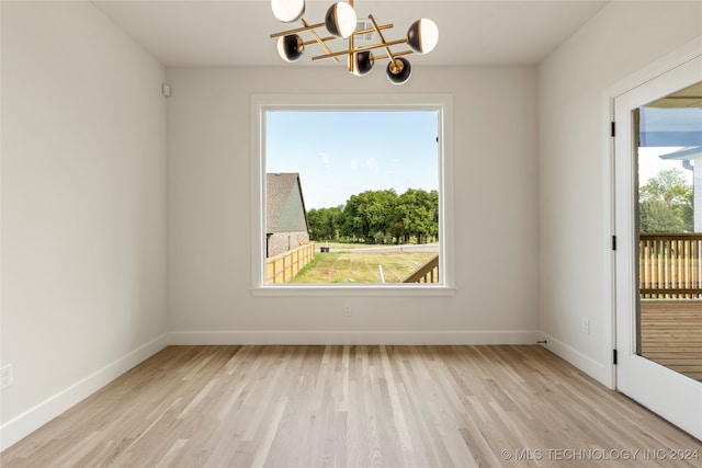 unfurnished room featuring light hardwood / wood-style flooring and a chandelier