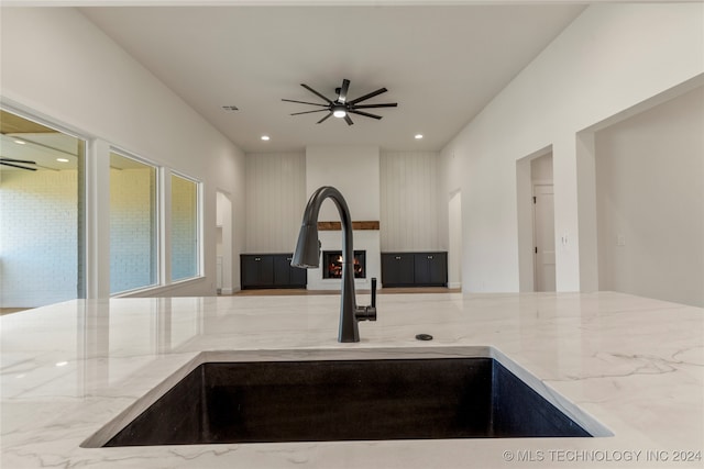 kitchen with light stone countertops, sink, and ceiling fan