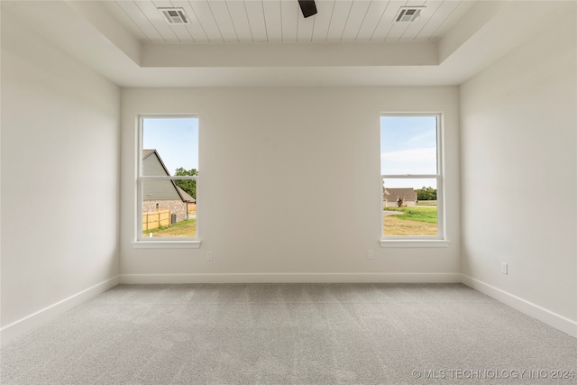 unfurnished room with wooden ceiling, a tray ceiling, light carpet, and ceiling fan