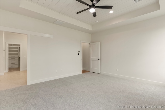 carpeted empty room featuring a tray ceiling, ceiling fan, and wood ceiling