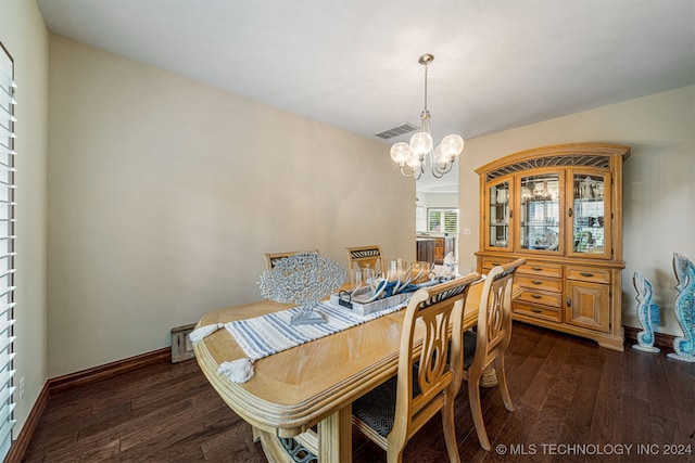 dining area featuring dark wood-type flooring and an inviting chandelier