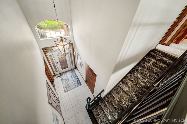 staircase with a towering ceiling and tile patterned floors