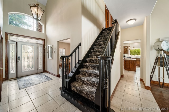 tiled foyer with a high ceiling and a chandelier