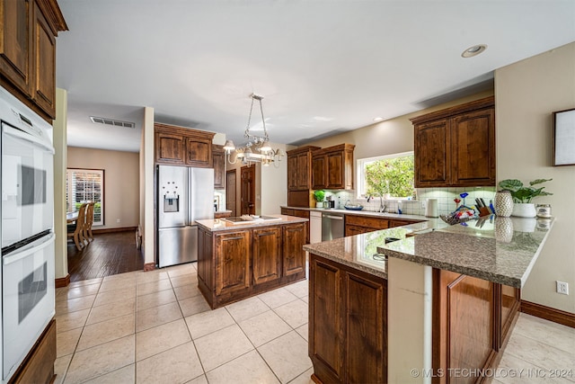 kitchen featuring a chandelier, backsplash, stainless steel appliances, decorative light fixtures, and a kitchen island