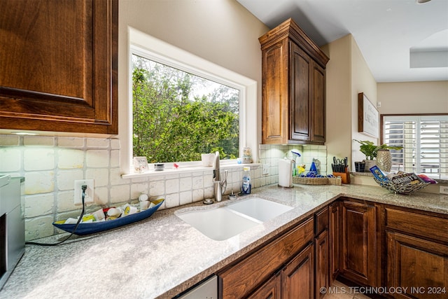 kitchen featuring backsplash, light stone counters, and sink