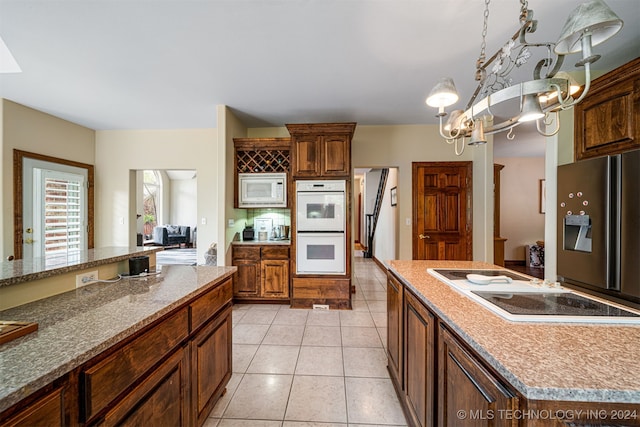 kitchen with a kitchen island, a notable chandelier, white appliances, and light tile patterned flooring