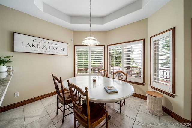 dining area featuring a wealth of natural light, a raised ceiling, and light tile patterned flooring