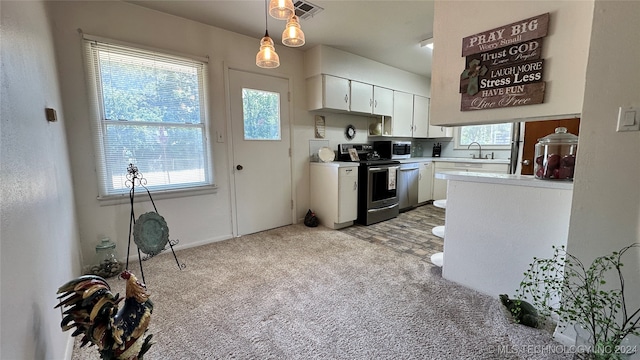 kitchen with light carpet, decorative light fixtures, sink, appliances with stainless steel finishes, and white cabinets