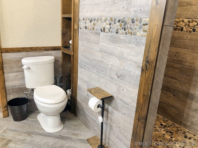 bathroom featuring tile walls, toilet, and a shower