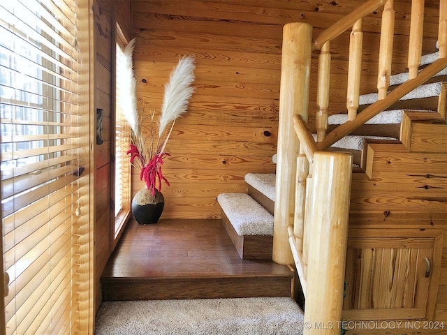 staircase featuring carpet flooring and wood walls