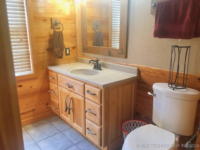 bathroom with vanity, toilet, wood walls, and tile patterned floors