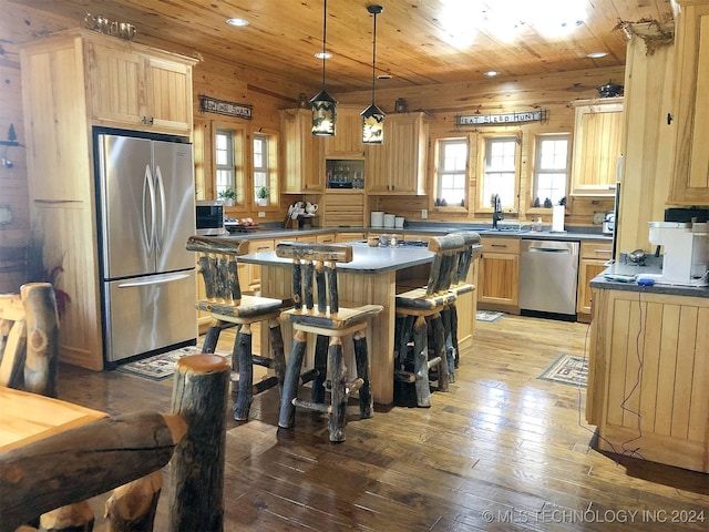 kitchen with appliances with stainless steel finishes, wood-type flooring, a kitchen island, and wooden walls