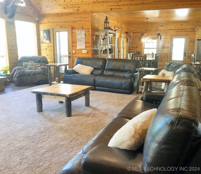 living room with wooden walls, a chandelier, carpet, wooden ceiling, and lofted ceiling