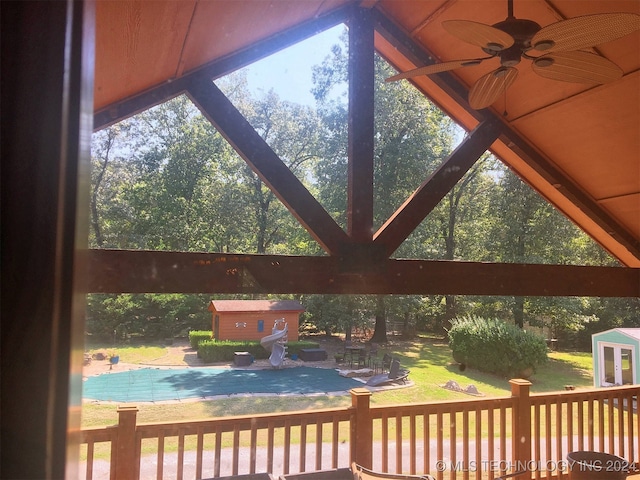 exterior space featuring a storage unit, a yard, and ceiling fan