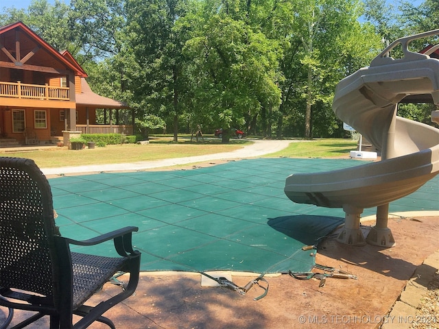 view of swimming pool featuring a water slide and a yard