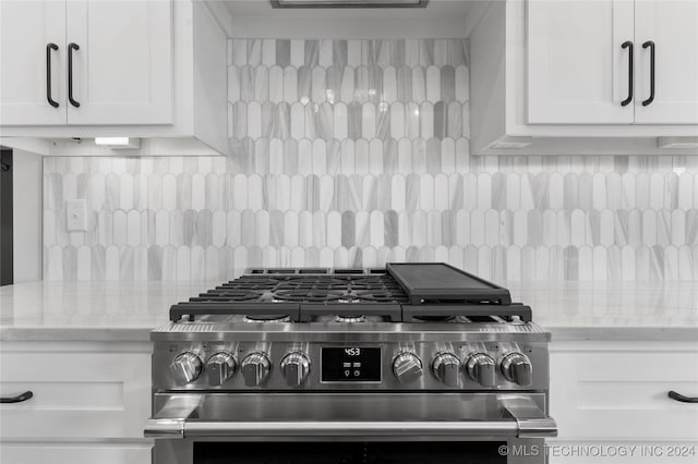 details featuring light stone counters, high end range, and white cabinets