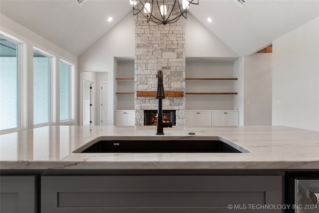 kitchen featuring gray cabinetry, light stone counters, and a chandelier