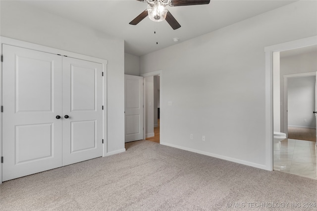 unfurnished bedroom with light colored carpet, connected bathroom, ceiling fan, and a closet