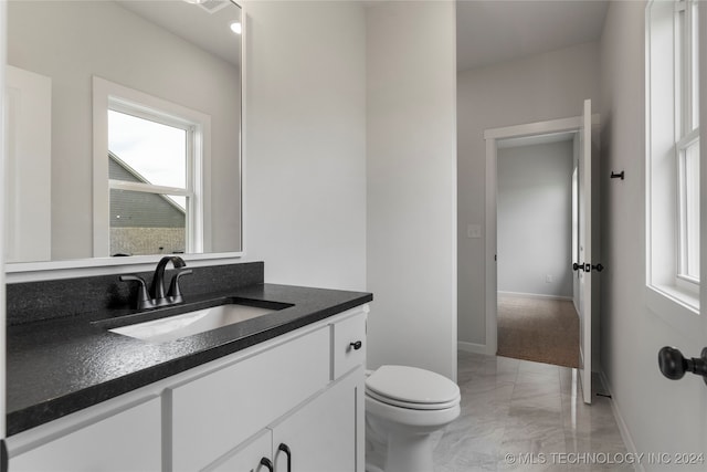 bathroom with a wealth of natural light, vanity, and toilet