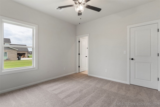 spare room featuring light carpet, a healthy amount of sunlight, and ceiling fan