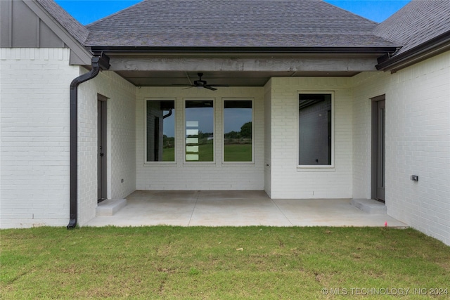 entrance to property featuring a lawn, ceiling fan, and a patio