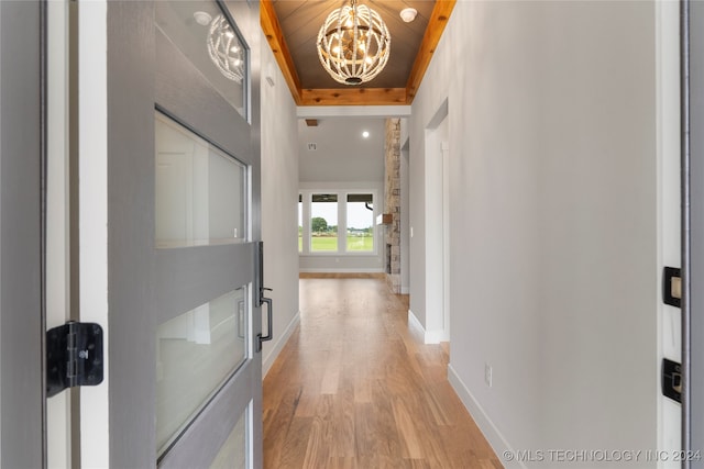 hallway featuring light hardwood / wood-style floors, wood ceiling, and an inviting chandelier