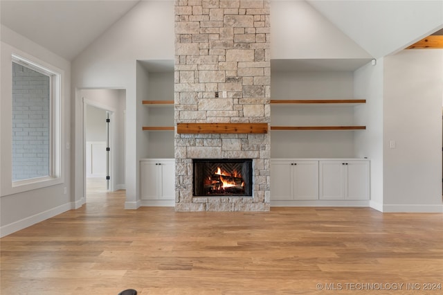 unfurnished living room featuring built in features, light hardwood / wood-style floors, high vaulted ceiling, and a fireplace