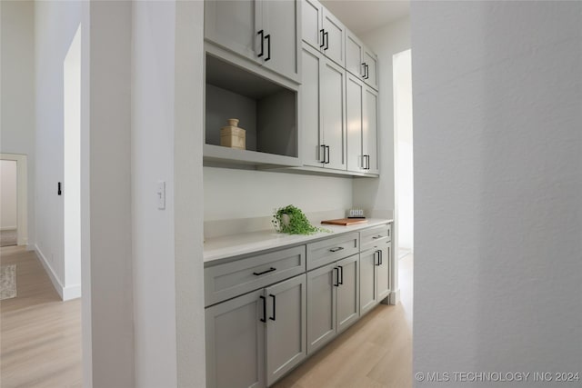 bar featuring gray cabinets and light hardwood / wood-style flooring