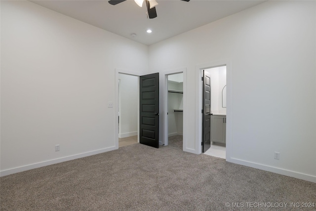 unfurnished bedroom with ensuite bath, light colored carpet, ceiling fan, a spacious closet, and a closet