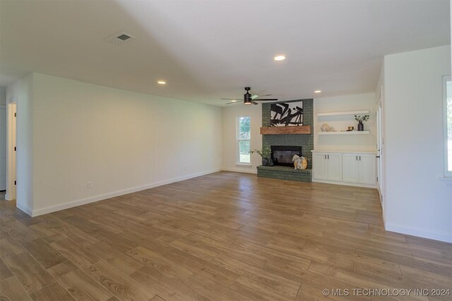 unfurnished living room with ceiling fan, a fireplace, and light hardwood / wood-style floors