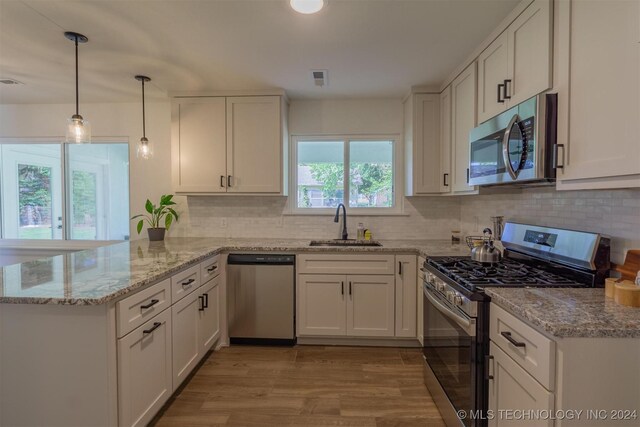 kitchen featuring light hardwood / wood-style flooring, stainless steel appliances, sink, kitchen peninsula, and white cabinetry