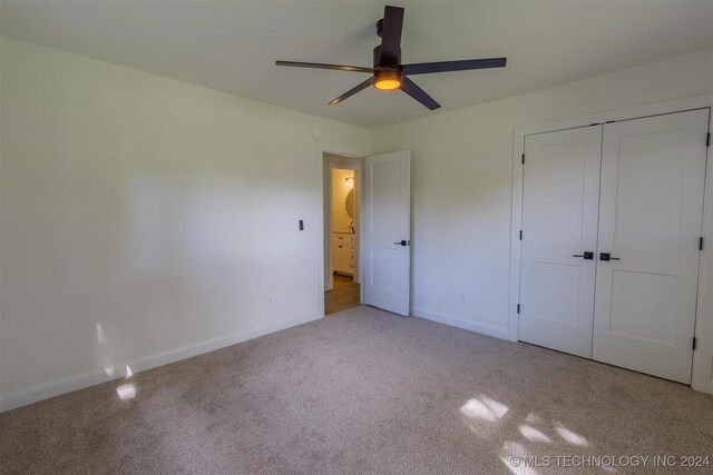 unfurnished bedroom featuring light carpet, ceiling fan, and a closet