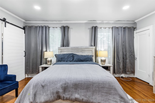 bedroom featuring crown molding, a barn door, and dark wood-type flooring