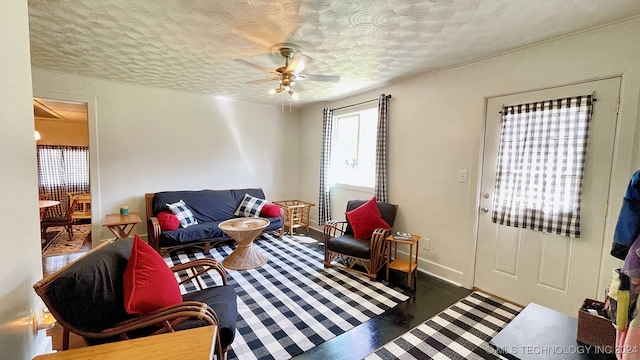 living room with a textured ceiling, dark wood-type flooring, and ceiling fan