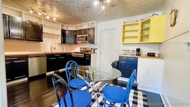 kitchen featuring ornamental molding, sink, appliances with stainless steel finishes, a textured ceiling, and dark hardwood / wood-style flooring